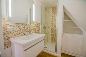 un bagno bianco con lavandino e doccia di Haus Heefkant Whg 10 a Rantum