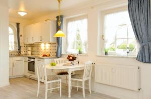 cocina con mesa blanca, sillas y ventanas en Haus Heefkant Whg 5, en Rantum