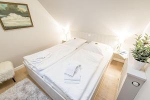 ein weißes Bett in einem Zimmer mit einer Pflanze in der Unterkunft Witthues Miin Luett in Wenningstedt-Braderup