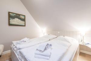 ein weißes Bett mit Handtüchern auf dem Zimmer in der Unterkunft Witthues Miin Luett in Wenningstedt-Braderup