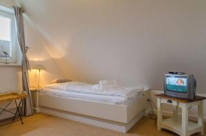 - une chambre avec un lit et une télévision sur une table dans l'établissement Senwai Hues Whg 3, à Westerland