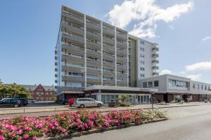 a large apartment building on a street with flowers at Hanseatenhaus_ Whg_ 84 _Meerblick_ in Westerland (Sylt)