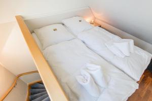 uma cama num quarto com lençóis brancos e almofadas em Art your Life Bundiswung Whg 2 em Westerland
