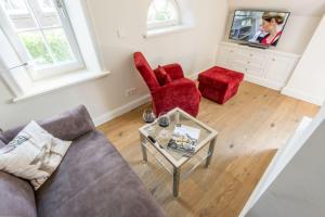 een woonkamer met een bank, 2 stoelen en een tv bij Haus Victor Whg 4 in Westerland