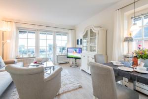 een woonkamer met een tafel en stoelen en een televisie bij Oceanview in Kampen