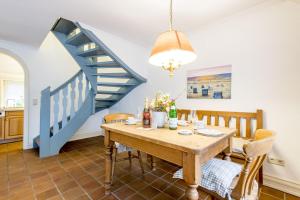 a dining room with a table and a blue staircase at Friesenhaus Kaeptn Hahn Hausteil 1 in Westerland