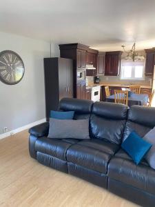 a living room with a leather couch and a kitchen at Maison Carofanne in Saint-Siméon