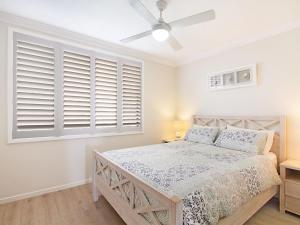 een slaapkamer met een bed en een raam met luiken bij Kirra Vista Apartments Unit 18 in Gold Coast