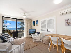 een woonkamer met een tafel en stoelen en een televisie bij Kirra Vista Apartments Unit 18 in Gold Coast