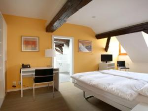 Schlafzimmer mit einem Schreibtisch und einem Bett mit gelben Wänden in der Unterkunft Auberge de Prangins in Prangins
