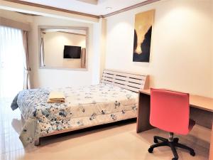 a bedroom with a bed and a desk and a red chair at Sea view apartment Jomtien beach condominium 12th Floor in Jomtien Beach +17 photos