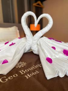 two white towels shaped like swans sitting on a table at Geo Boutique Hotel - Seri Kembangan in Seri Kembangan