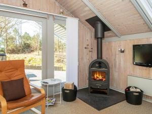 スナーヴィグにあるThree-Bedroom Holiday home in Ringkøbing 26の暖炉付きのパティオ(テレビ、椅子付)