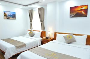 ein Hotelzimmer mit 2 Betten und einem Fenster in der Unterkunft Khách sạn KIM NGÂN in Quy Nhon