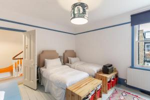 1 dormitorio con 2 camas, mesa y ventana en Lovely 4-Bedroom House near Portobello, en Londres