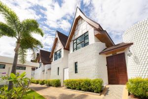 アオナンビーチにあるPoonsiri Varich Pool Villa Aonangの茶色の扉とヤシの木がある白い家