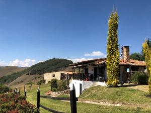 una casa en una colina con una valla y un árbol en Casa Aposentos - Finca Camino al Cielo, en Suesca