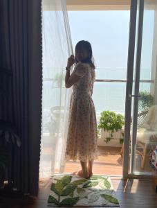 una joven parada frente a una ventana en Ocean Eyes - Gold Sea Vung Tau Building en Vung Tau
