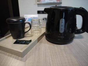 a black coffee maker and a cup on a counter at Hotel Route-Inn Yonago in Yonago