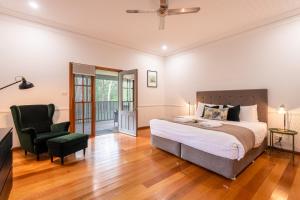 a bedroom with a large bed and a chair at Bay and Bush Cottages Jervis Bay in Huskisson