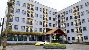 巴吞他尼Hotel IYA的一座白色的大建筑,前面有一辆汽车