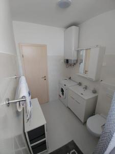 ein weißes Badezimmer mit einem Waschbecken und einer Waschmaschine in der Unterkunft Apartmani Valuna in Privlaka