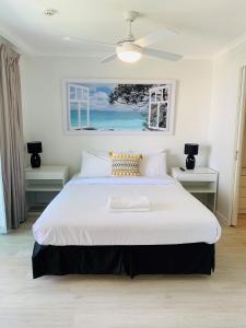 a bedroom with a large white bed with a ceiling fan at Emerald Sands Holiday Apartments in Gold Coast