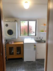 eine kleine Küche mit einem weißen Kühlschrank und einem Fenster in der Unterkunft The Red Door in Mount Gambier