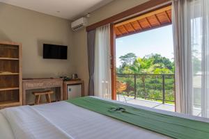 a bedroom with a bed and a large window at Alam Kawi Ubud Resort & Spa in Gianyar