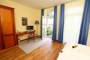 a bedroom with a bed and a desk with a computer at STADE LAND GOLF HOTEL Tiny Häuser in Deinste