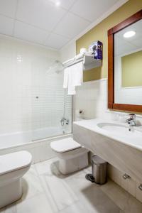 a bathroom with a sink and a toilet and a mirror at Hotel Las Casas del Duque in Osuna