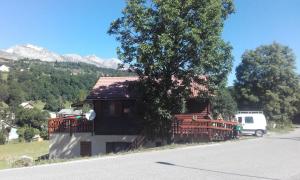 a house with people sitting on a balcony next to a tree at Chalet Lisa - 10 PERSONNES - PISTE 5MN EN VOITURE in Agnières-en-Dévoluy