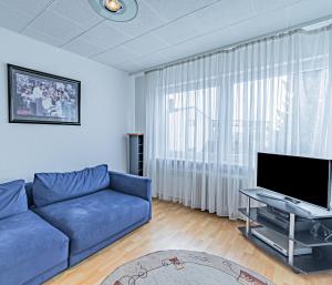 a living room with a blue couch and a tv at Hotel Tannenblick in Bad Vilbel