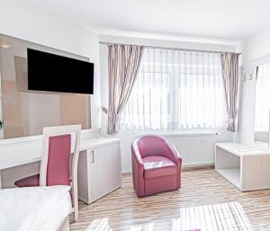 a hotel room with a bed and a chair at Hotel Tannenblick in Bad Vilbel