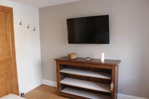 a living room with a television and a table with a shelf at Maison de charme en plein centre ville in Montreuil-sur-Mer