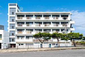 a white building with trees in front of it at Type A Room 123平米 -ウル エスポワール石垣- in Ishigaki Island