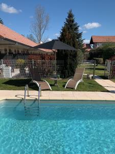 a swimming pool with two chairs and an umbrella at Hôtel Le Clos Badan in Nuits-Saint-Georges