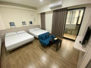 una camera d'albergo con due letti e una sedia blu di Enjoy House a Magong