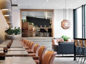 a restaurant with a row of tables and chairs at Hotel Oasia Aarhus City in Aarhus