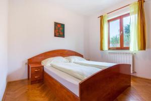 a bedroom with a bed with a wooden headboard and a window at Zoro in Baška