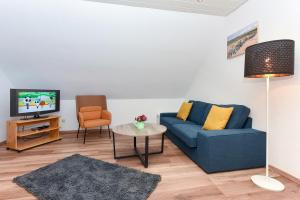 sala de estar con sofá azul y TV en Ferienwohnung Wattgeflüster, en Esens