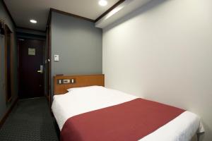 a bedroom with a bed with a red and white blanket at Kadoya Hotel in Tokyo