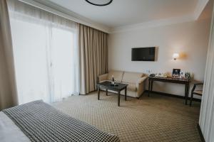 a hotel room with a bed and a couch and a television at Hotel Toscania in Włoszakowice