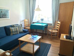 ein Wohnzimmer mit einem blauen Sofa und einem Tisch in der Unterkunft Gästehaus am Deich in Juist