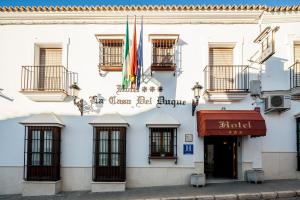 un edificio con banderas a un lado. en Hotel Las Casas del Duque, en Osuna