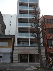 an apartment building with a tree in front of it at ケイアイコンホテルズ 久屋 in Nagoya
