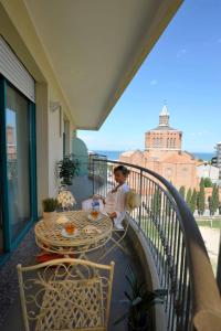 un hombre sentado en una mesa en un balcón en Bellariva Feeling Hotel, en Rímini