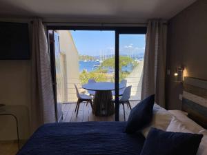 a bedroom with a bed and a table and a balcony at L'Arche de Porquerolles in Porquerolles