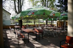 a group of tables and chairs under a green umbrella at Restoranas - Svečių Namai - Restaurant - Guest House Perkūnkiemis in Elektrėnai