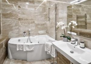 Baño blanco con bañera y lavamanos en LIRA EuApartments, en Grodno